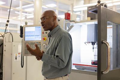 Instructor in front of a CNC machine speaking to a group of students